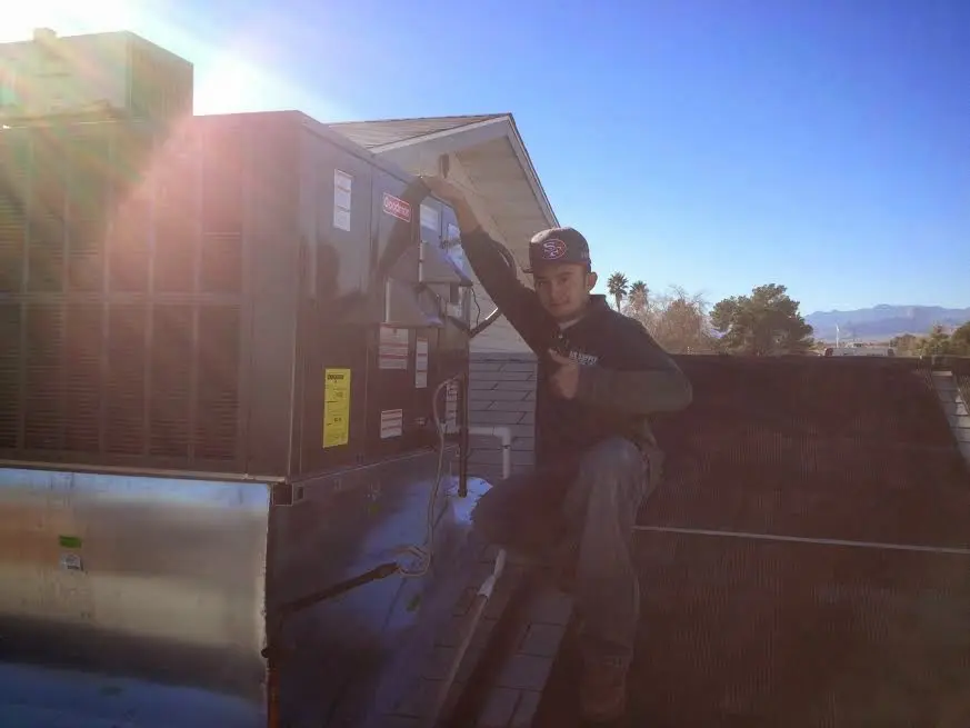 HVAC technician performing AC Tune-Up on a rooftop unit in Mason