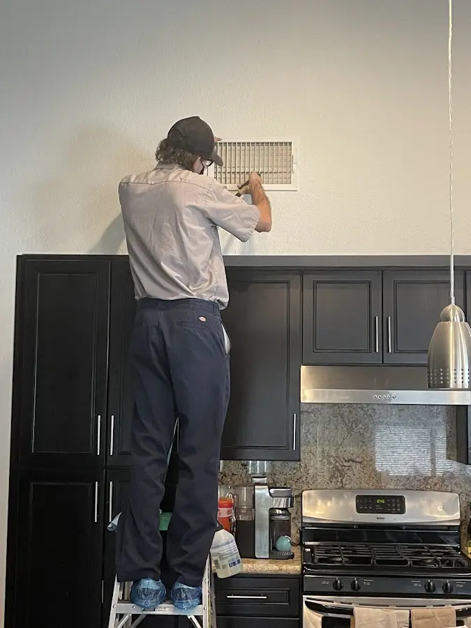 Technician inspecting an air vent during HVAC service in Mason